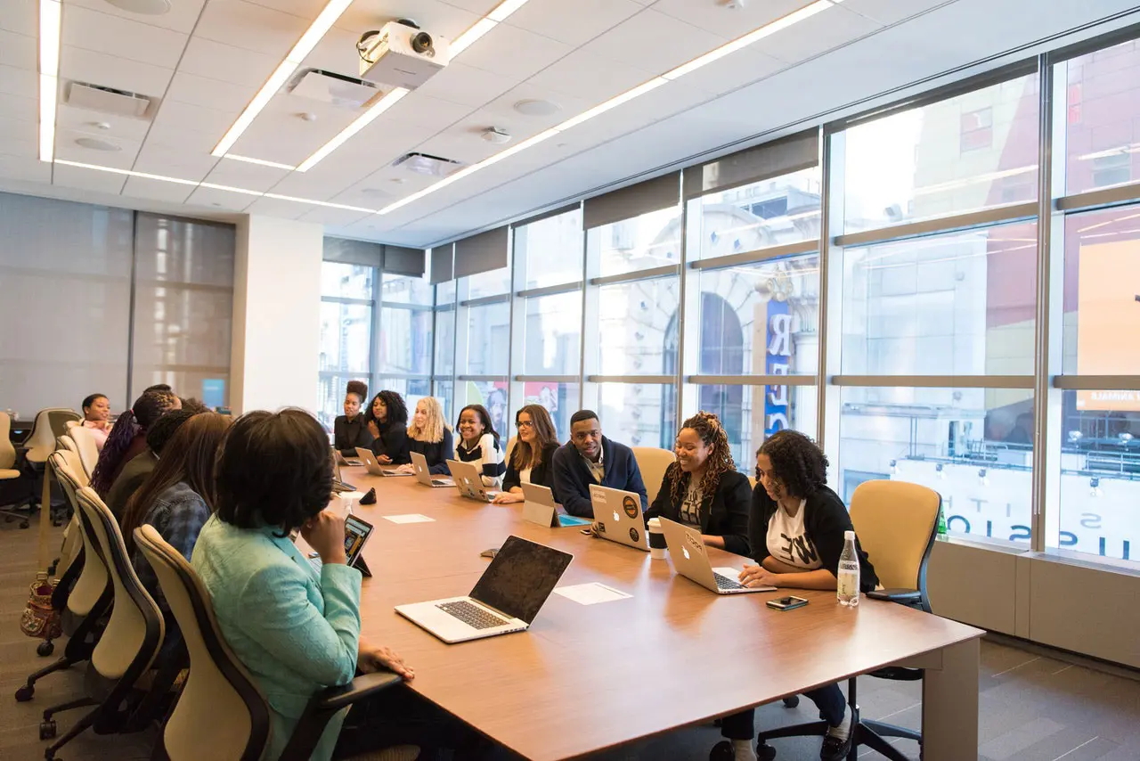 A group of people sitting at a table with laptops.