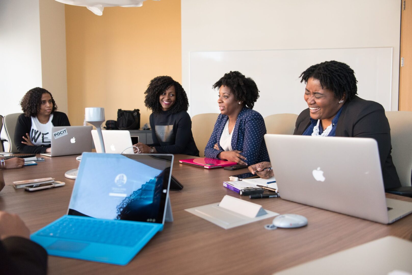 A group of people sitting at a table with laptops.